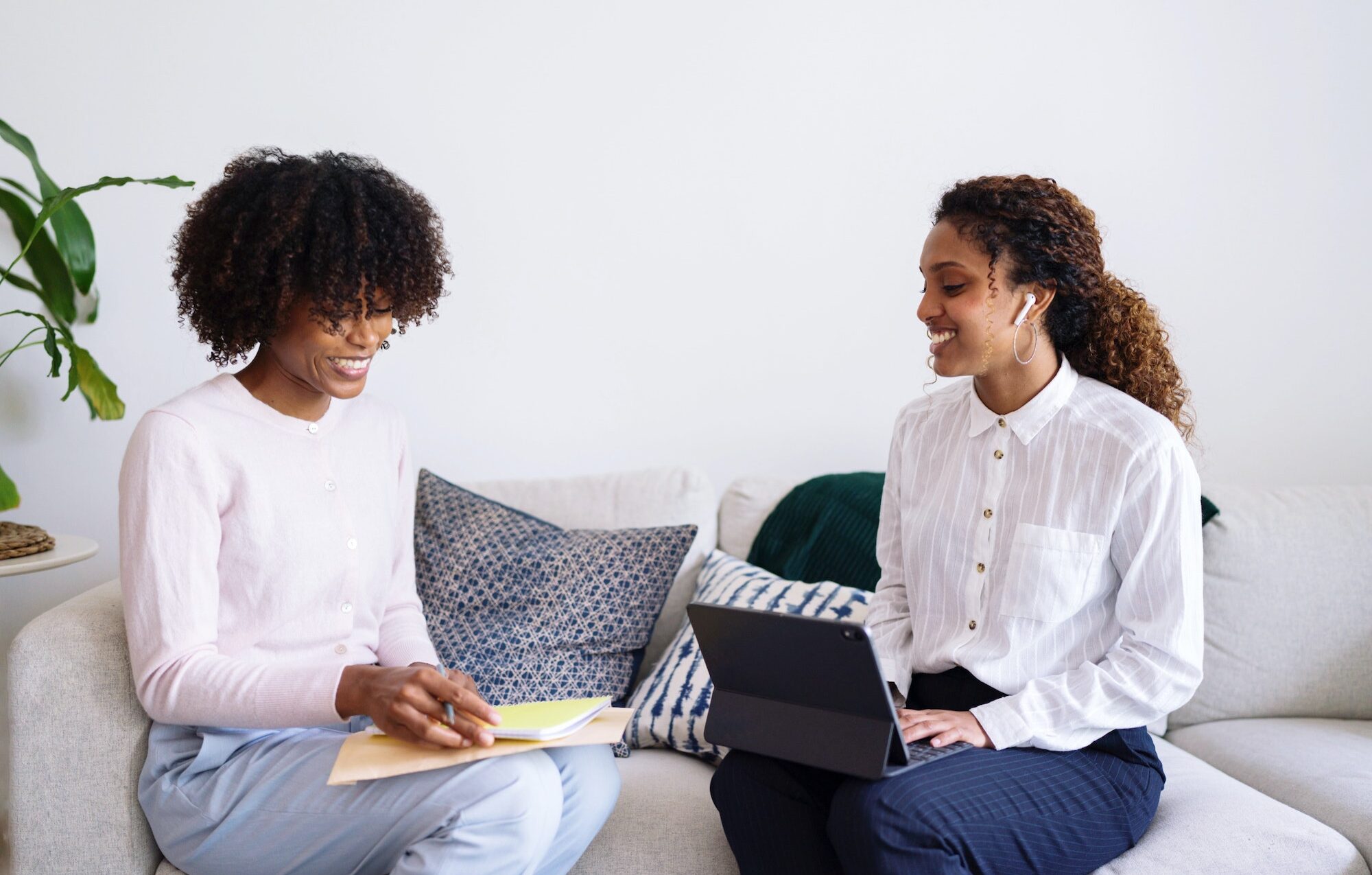 Two black women sitting down on the couch having an interview in a conversation