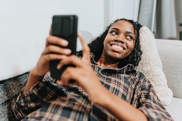 Woman is smiling and looking at her cell phone