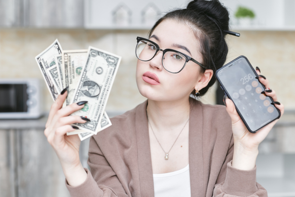 A woman holds a calculator and money.