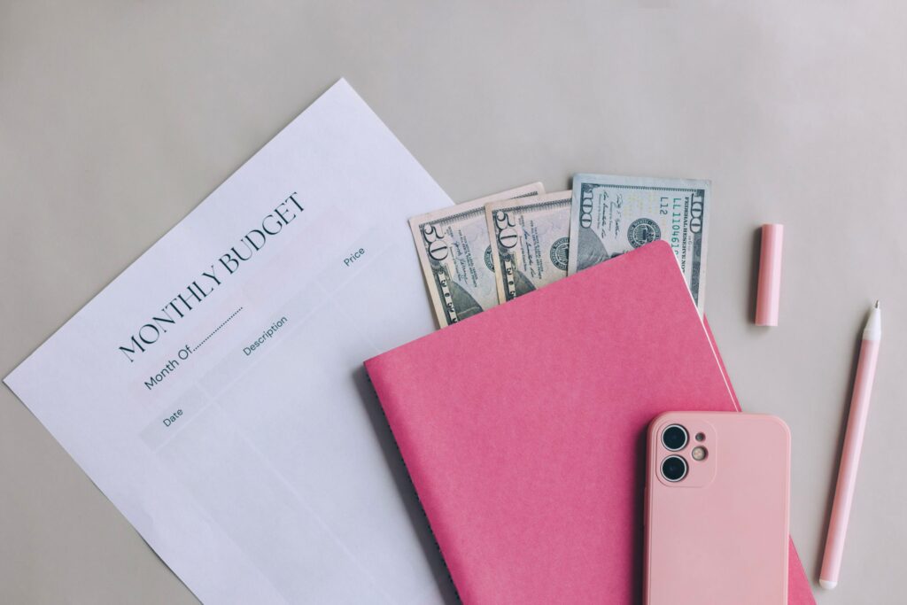 A pink calendar with $60 in twentys and a phone.