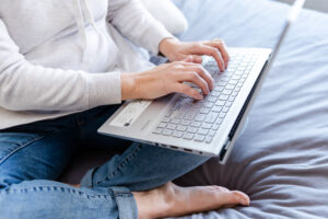 A woman's hands on a keyboard of a laptop working on her doula business.