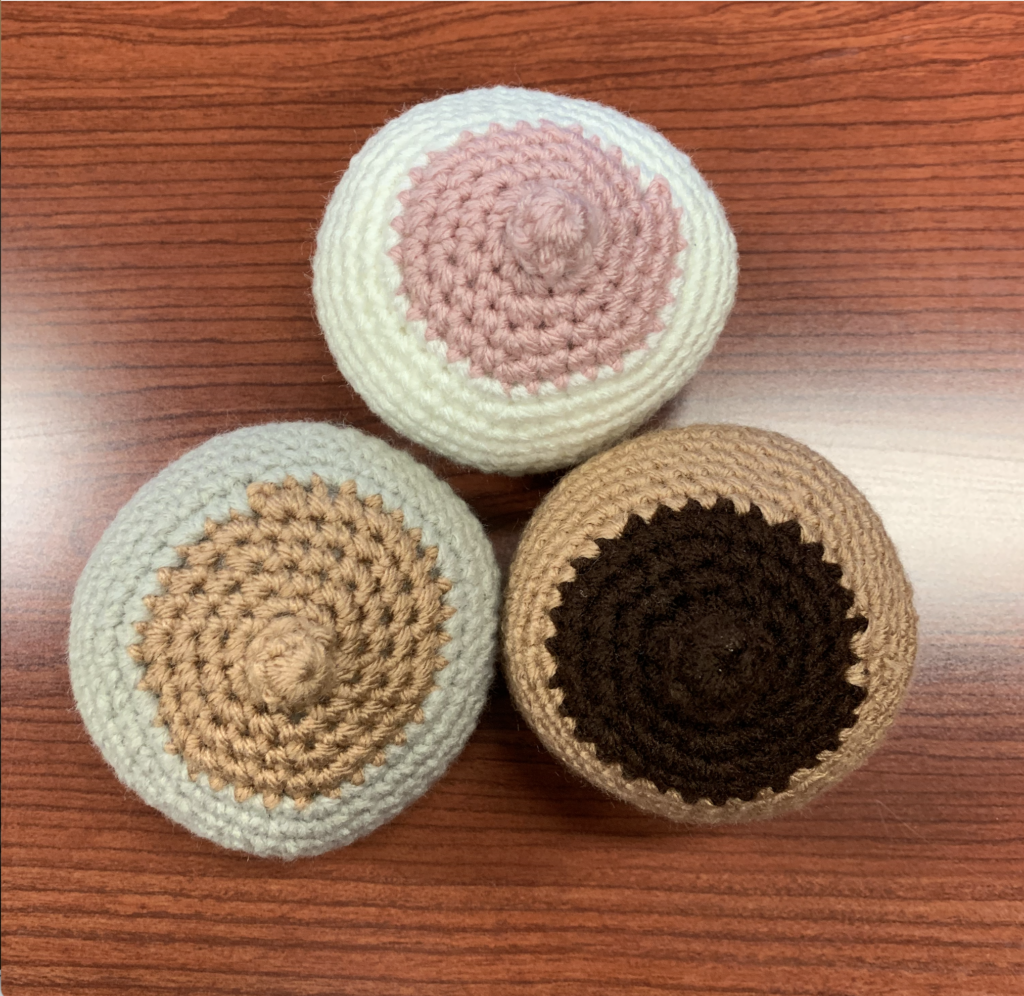 Three breasts that have been crocheted and are different colors.