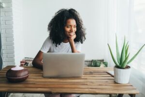 A woman stares off camera and she sits in front of a computer.