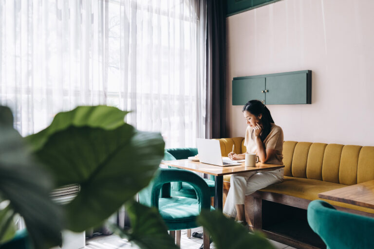 Woman sits in a coffee shop working on a computer.