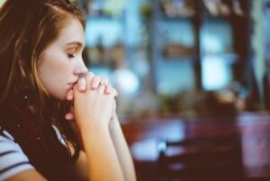 A woman looks down at the desk in thought.