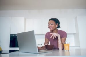 A woman smiles at her computer while considering doula training.