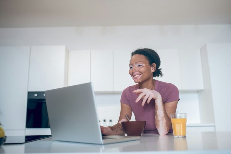 A woman smiles at her computer while considering doula training.