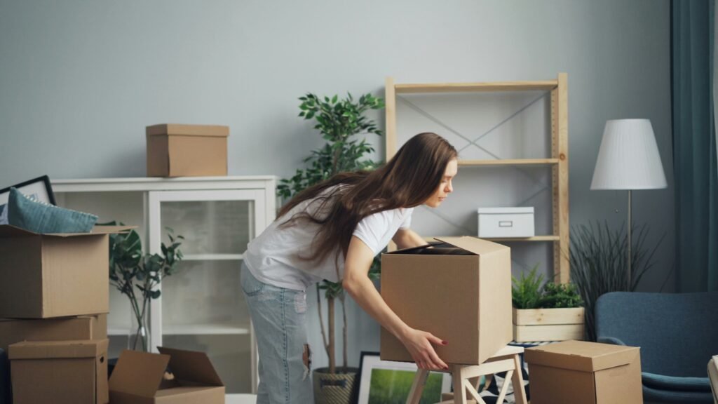 Woman lifting heavy moving boxes in the living room.