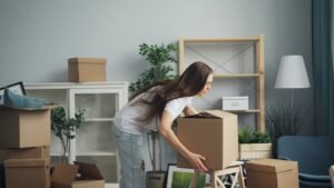 Woman lifting heavy moving boxes in the living room.