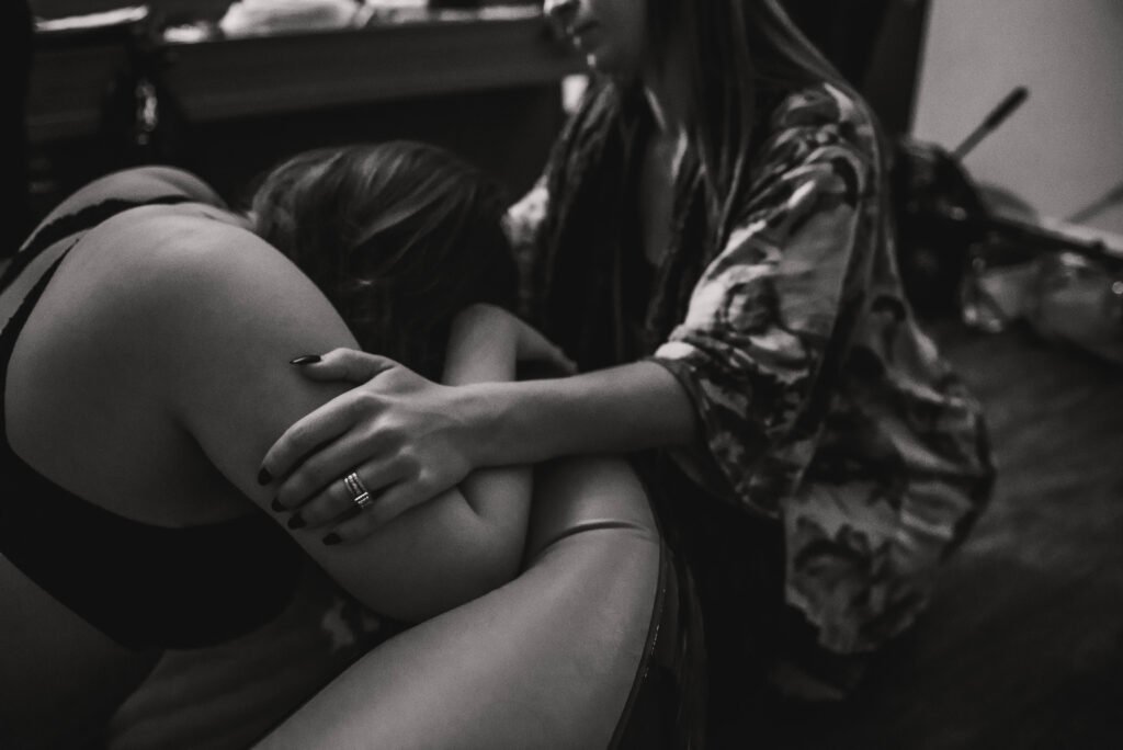 A doula rests a hand on a laboring person's back in a birth pool.