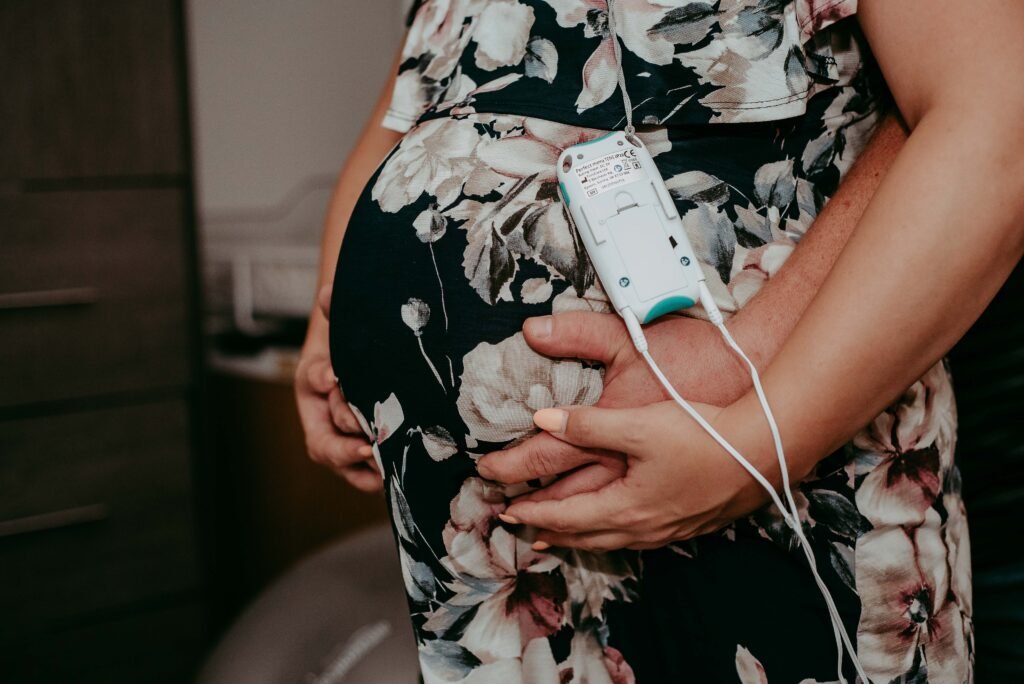 A laboring person wearing a TENS unit holds their belly.