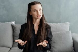A white woman in a brown blazer stares at the camera with her mouth slightly open.